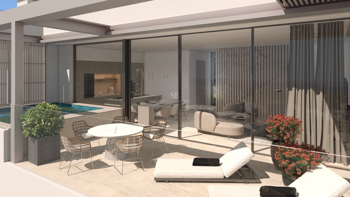 Terrasse moderne avec coin repas, chaises longues et petite piscine à côté du salon et de la cuisine vitrés.