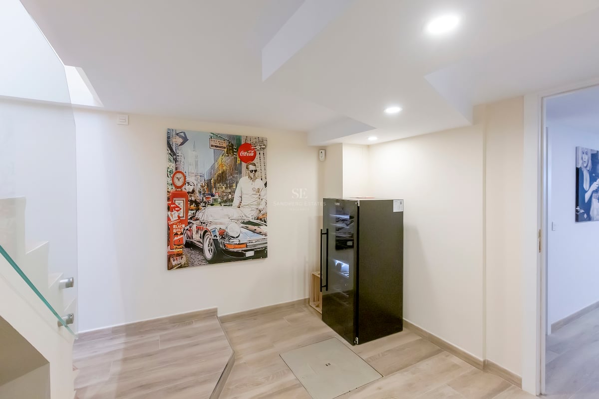 Intérieur moderne avec une peinture pop-art de voiture, une cave à vin noire et un escalier en verre.