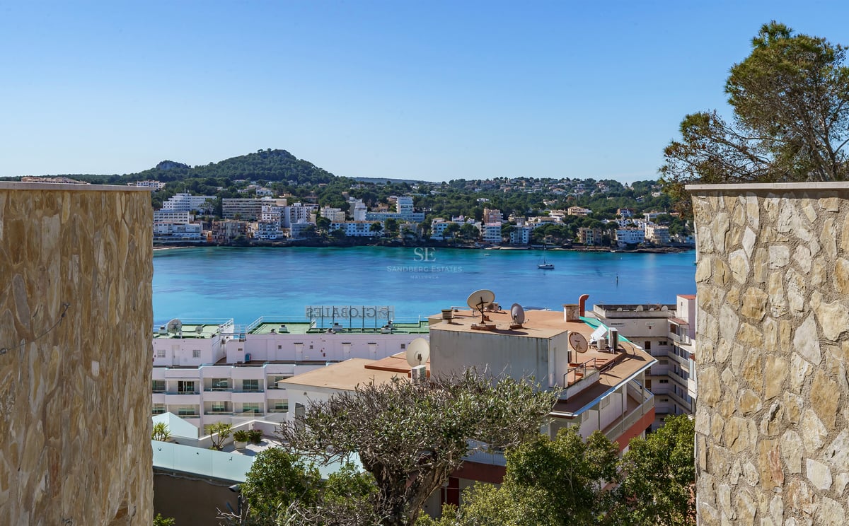 Vue d'une baie méditerranéenne turquoise encadrée par des murs en pierre naturelle sous un ciel bleu clair.