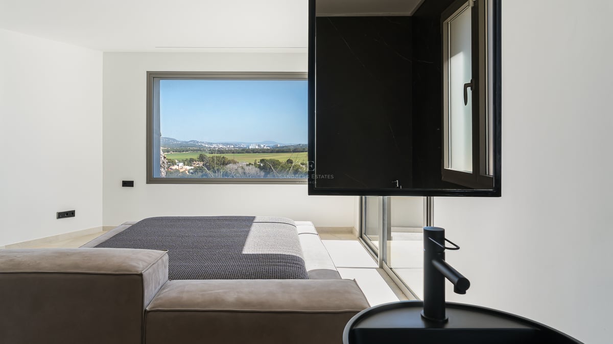 Chambre principale contemporaine avec vasque noire intégrée et grande fenêtre donnant sur une vallée verdoyante.