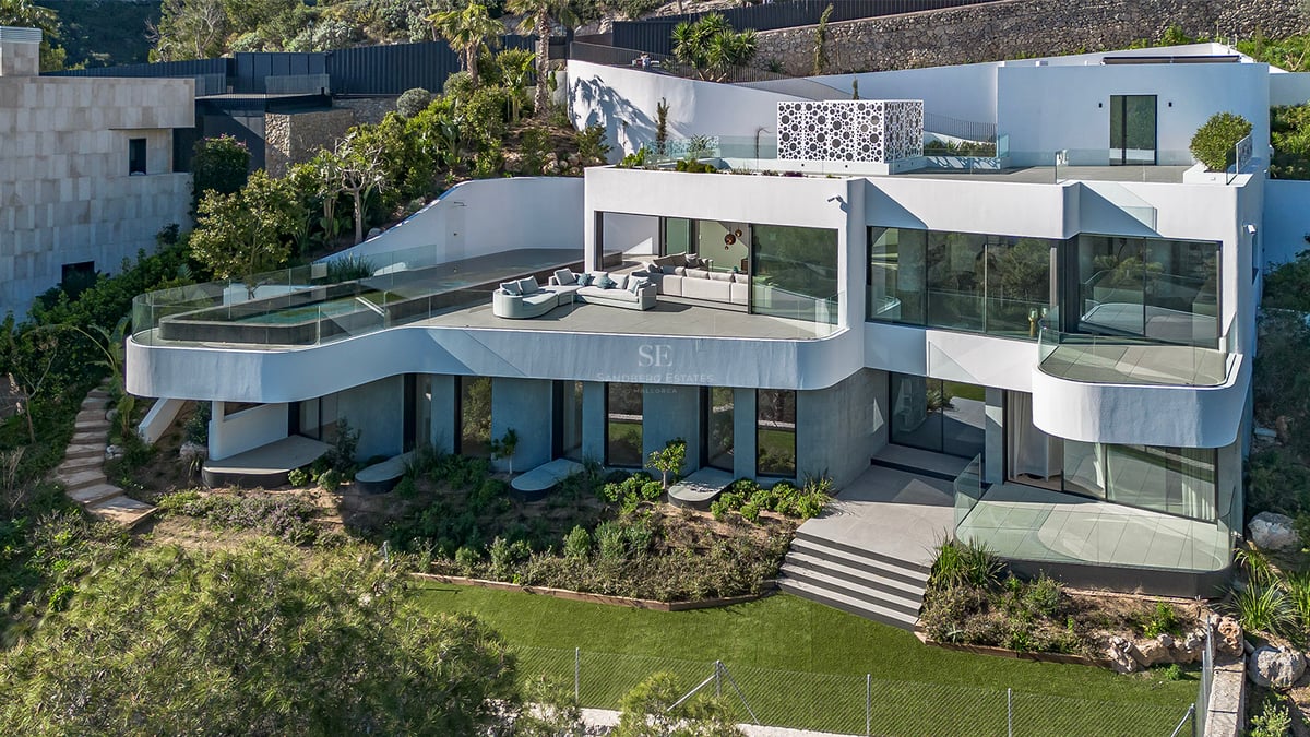 Villa blanche moderne à plusieurs niveaux avec piscine à débordement, terrasses courbes et jardins luxuriants.