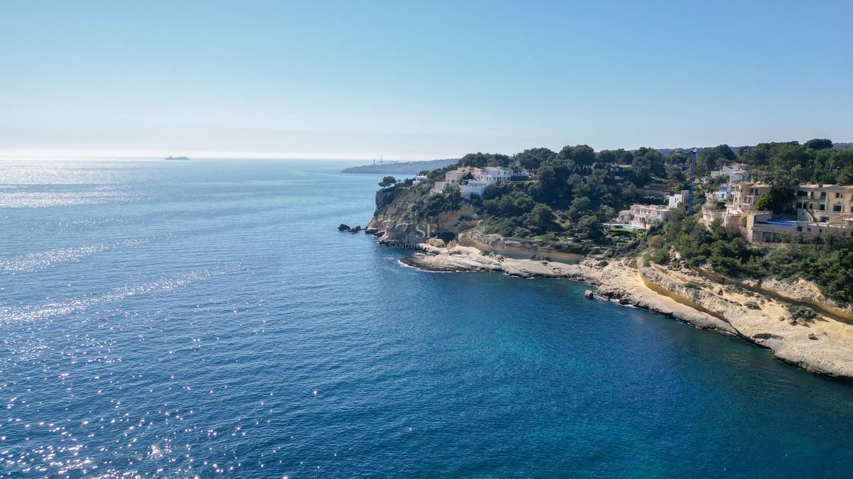 Vue par drone de falaises avec des villas de luxe surplombant la mer Méditerranée étincelante.