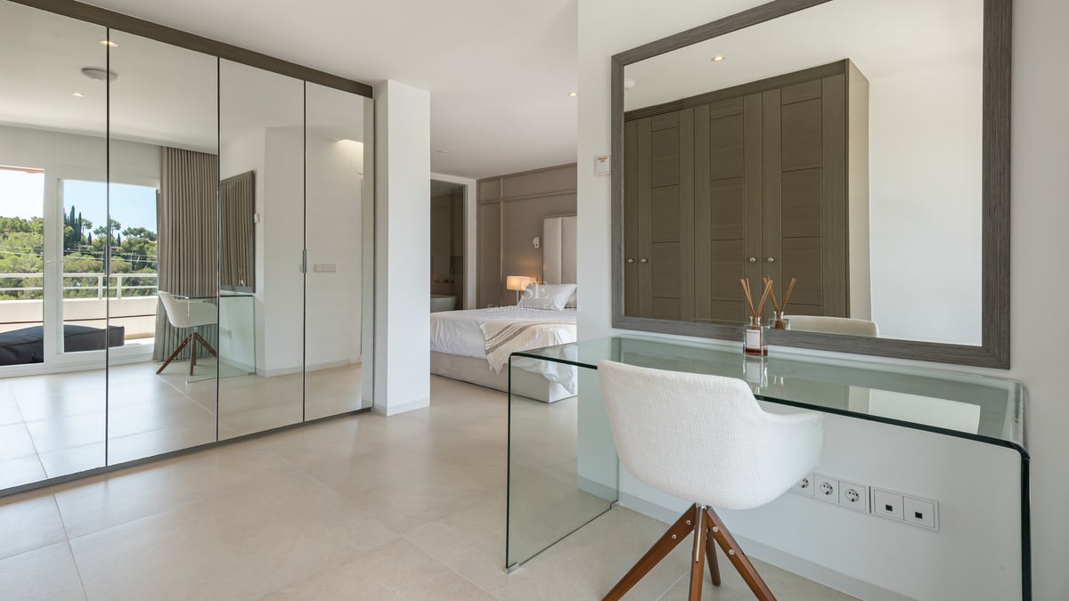 Chambre de maître moderne avec placards miroir, coiffeuse en verre et accès terrasse.