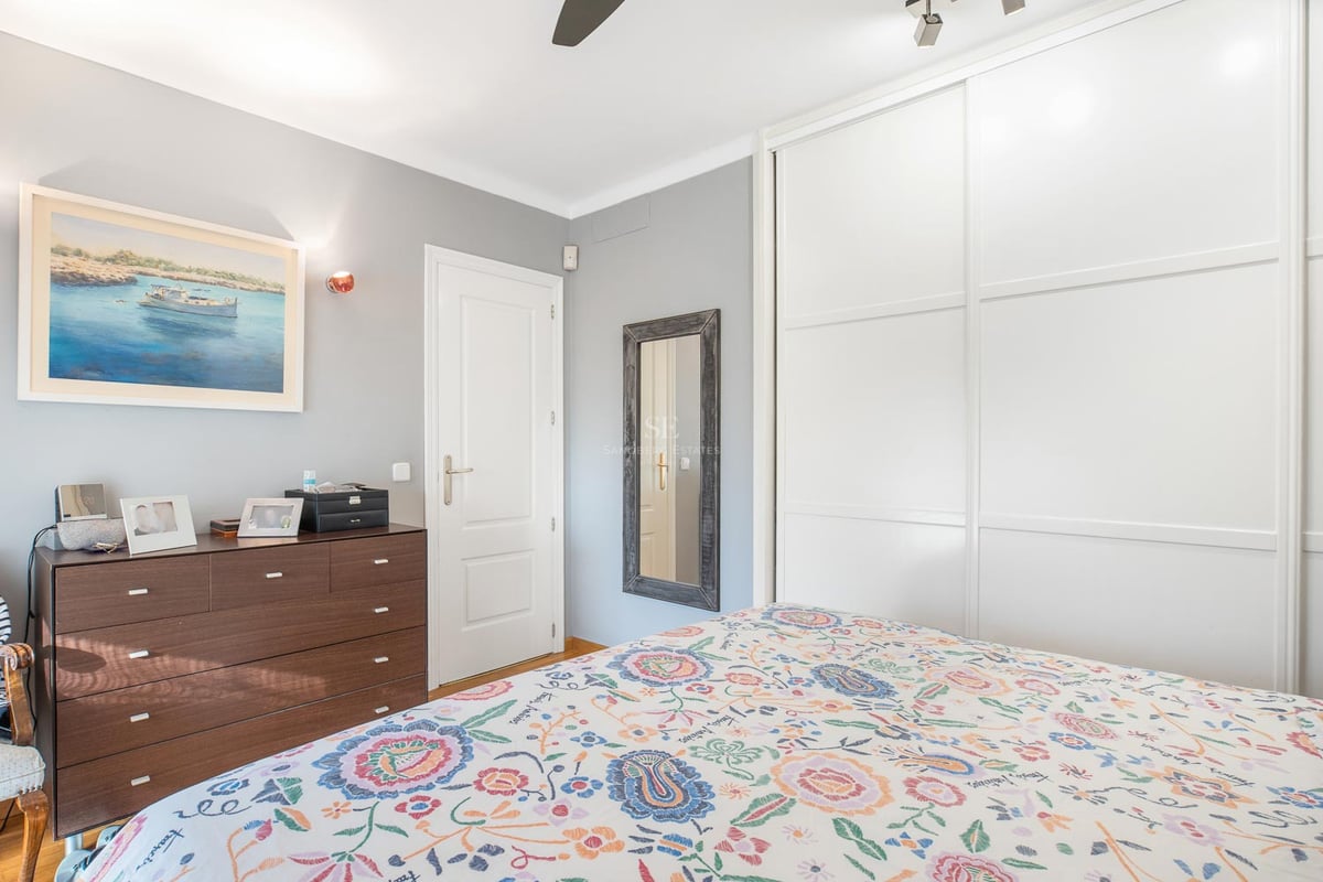 Chambre d'amis lumineuse avec grands placards coulissants blancs, commode en bois foncé et literie fleurie.