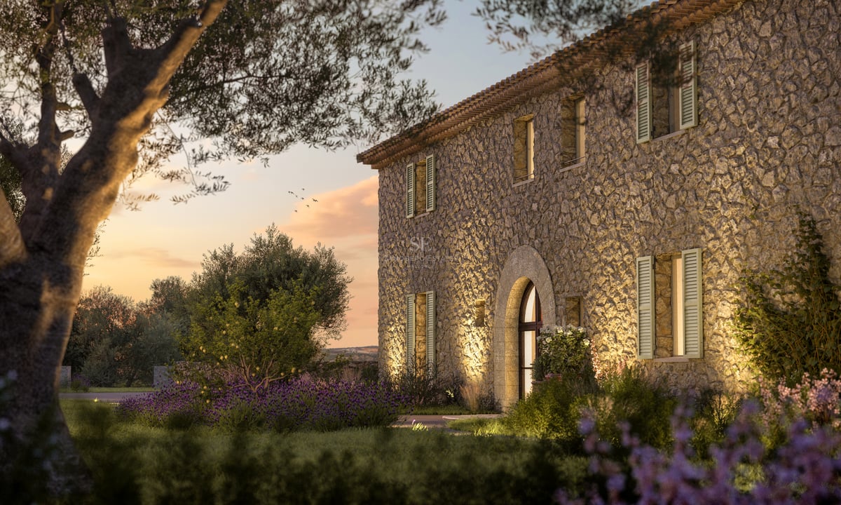 Façade en pierre d'une villa de luxe au coucher du soleil avec entrée voûtée et oliviers.