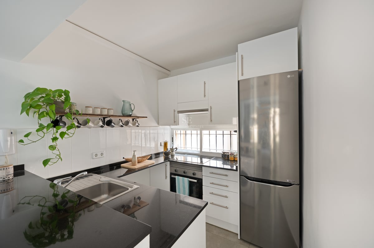 Cuisine contemporaine avec placards blancs, plans de travail en granit noir et appareils en acier inoxydable.