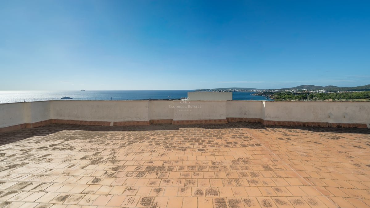 Toit-terrasse en terre cuite avec vue imprenable sur la mer Méditerranée et le littoral sous un ciel bleu.