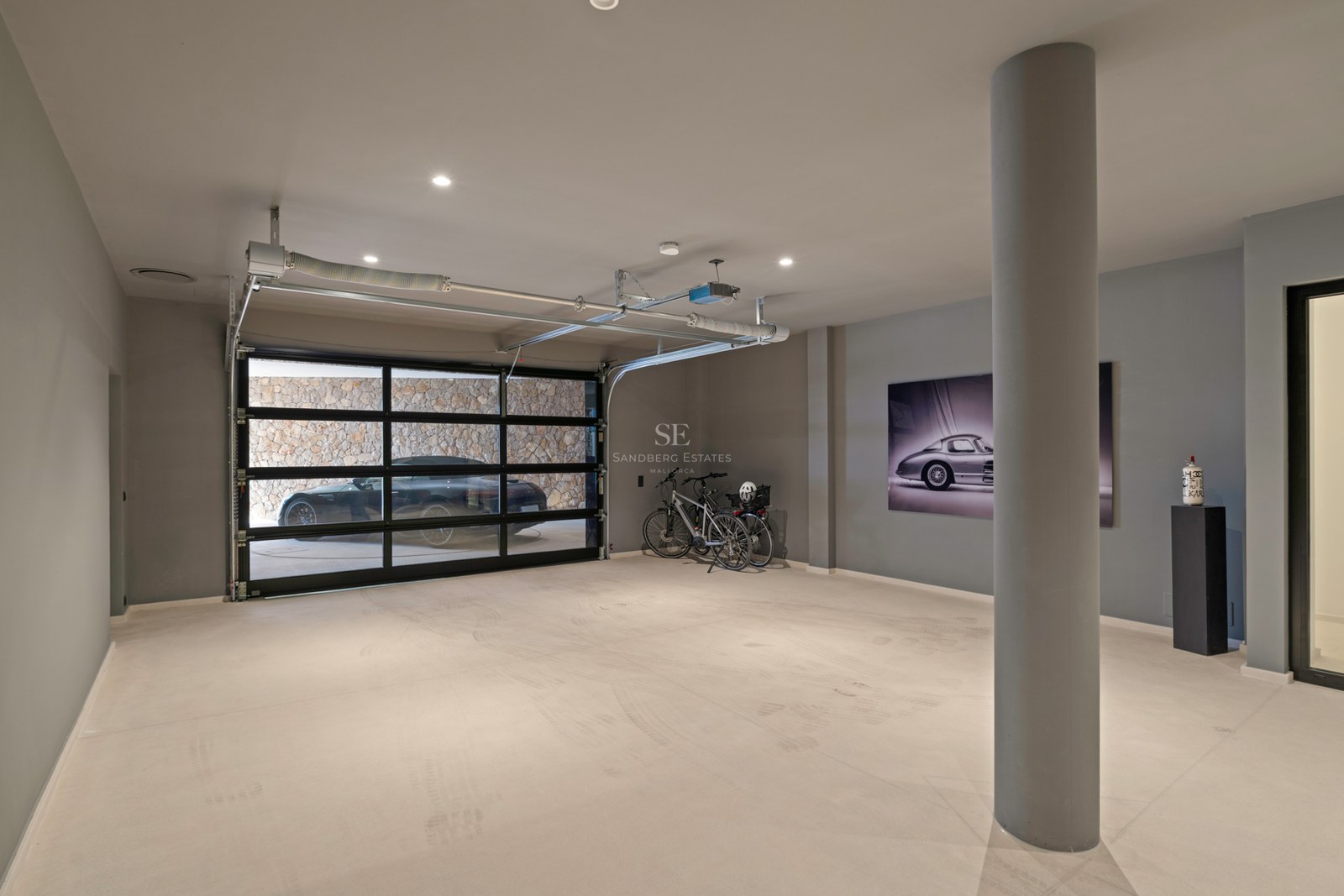 Rymligt modernt underjordiskt garage med sektionsdörr i glas, polerat betonggolv och infälld belysning.