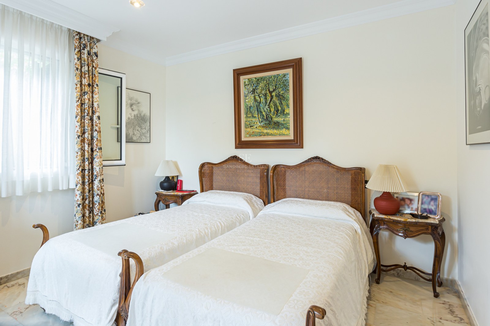 Bedroom featuring two twin beds with wicker headboards, marble flooring, and framed artwork.