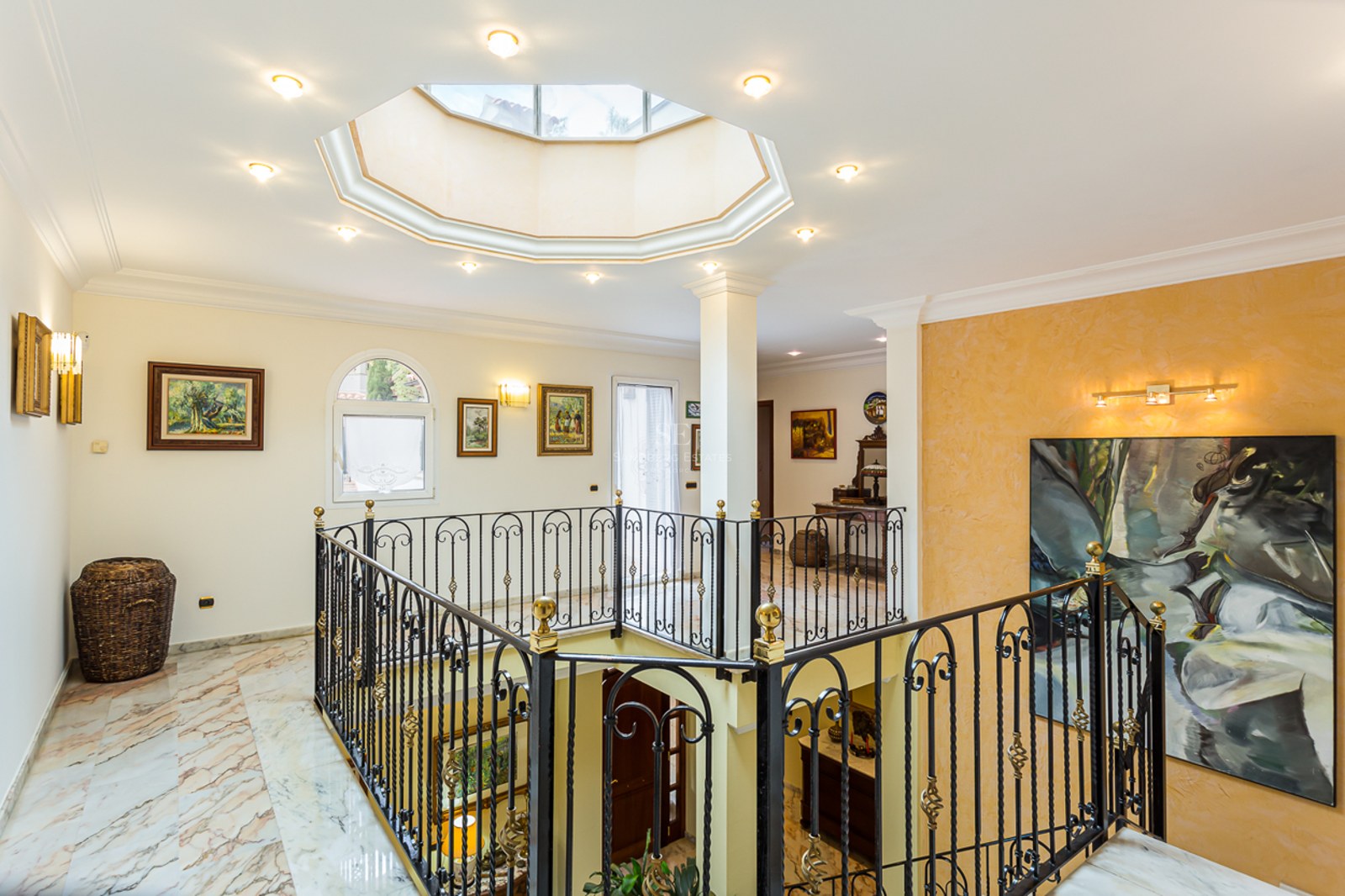 Interior landing with marble floors, a wrought iron railing, and an octagonal skylight in the ceiling.