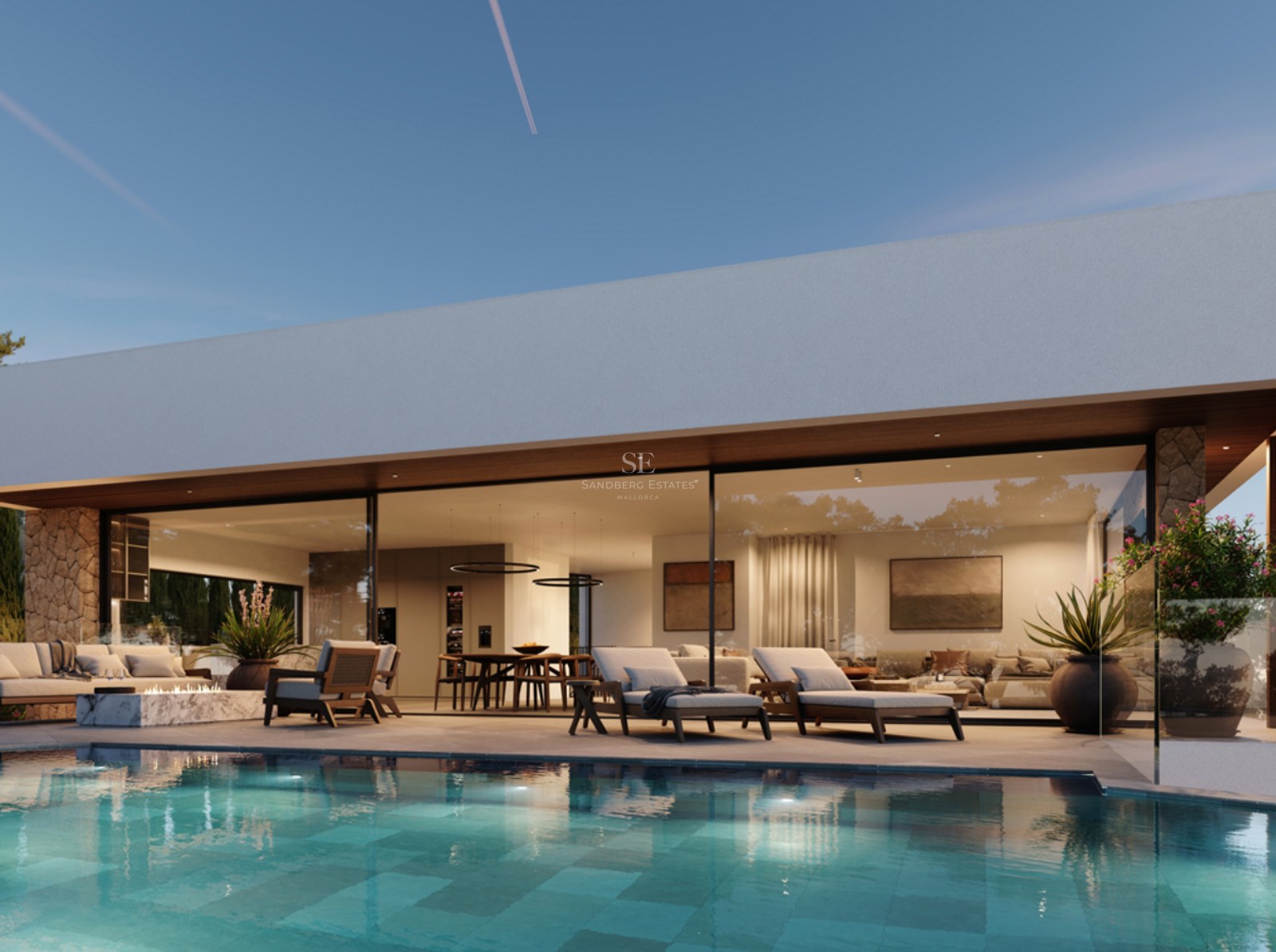 A modern turquoise swimming pool with sun loungers in front of a contemporary lit villa at dusk.
