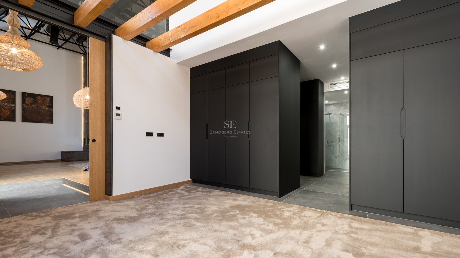 Dressing area featuring large black cabinets, exposed wooden ceiling beams, and plush beige carpeting.