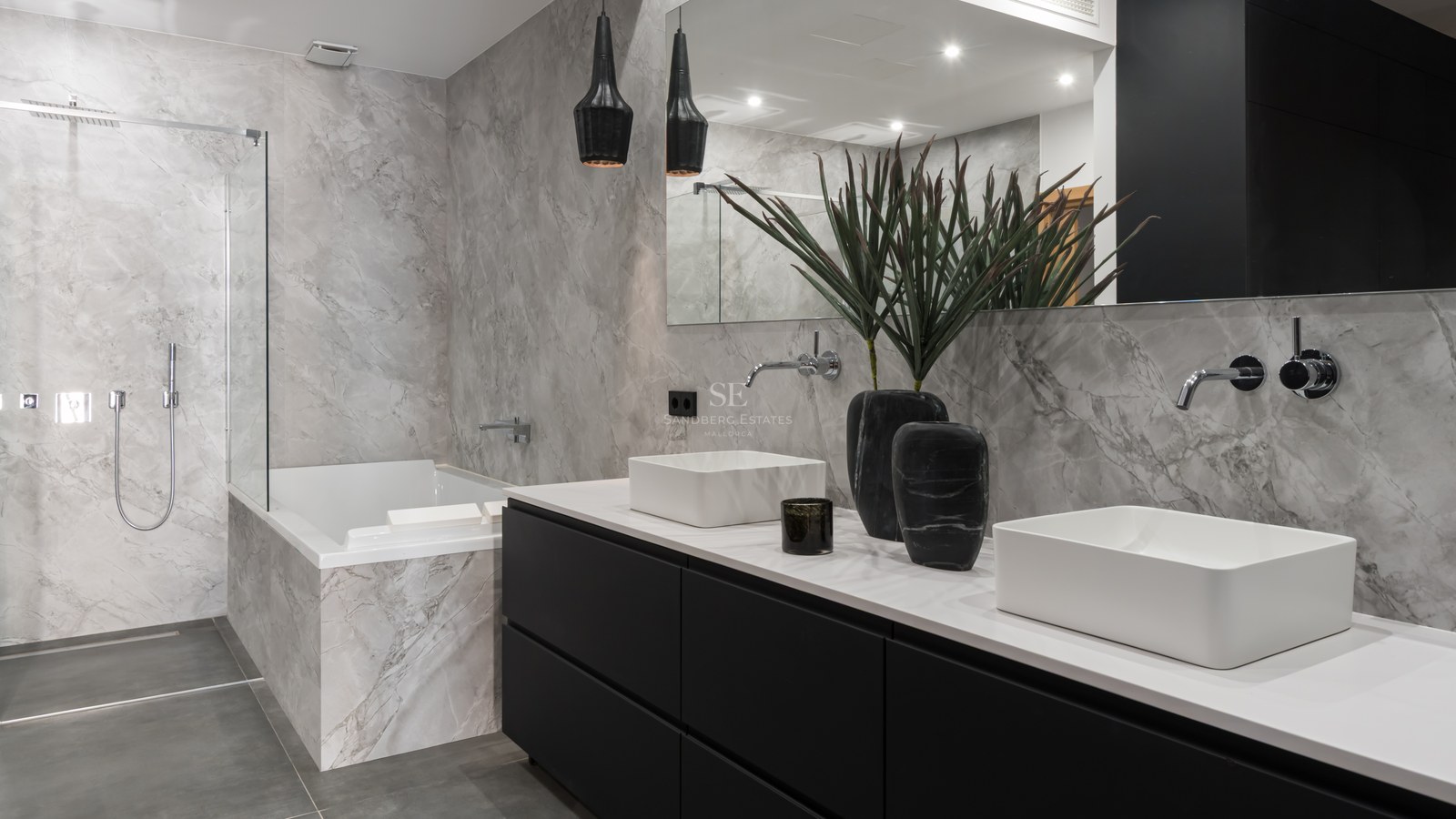 Luxury bathroom with double white sinks, black vanity, marble-tiled bathtub, and a glass-enclosed walk-in shower.