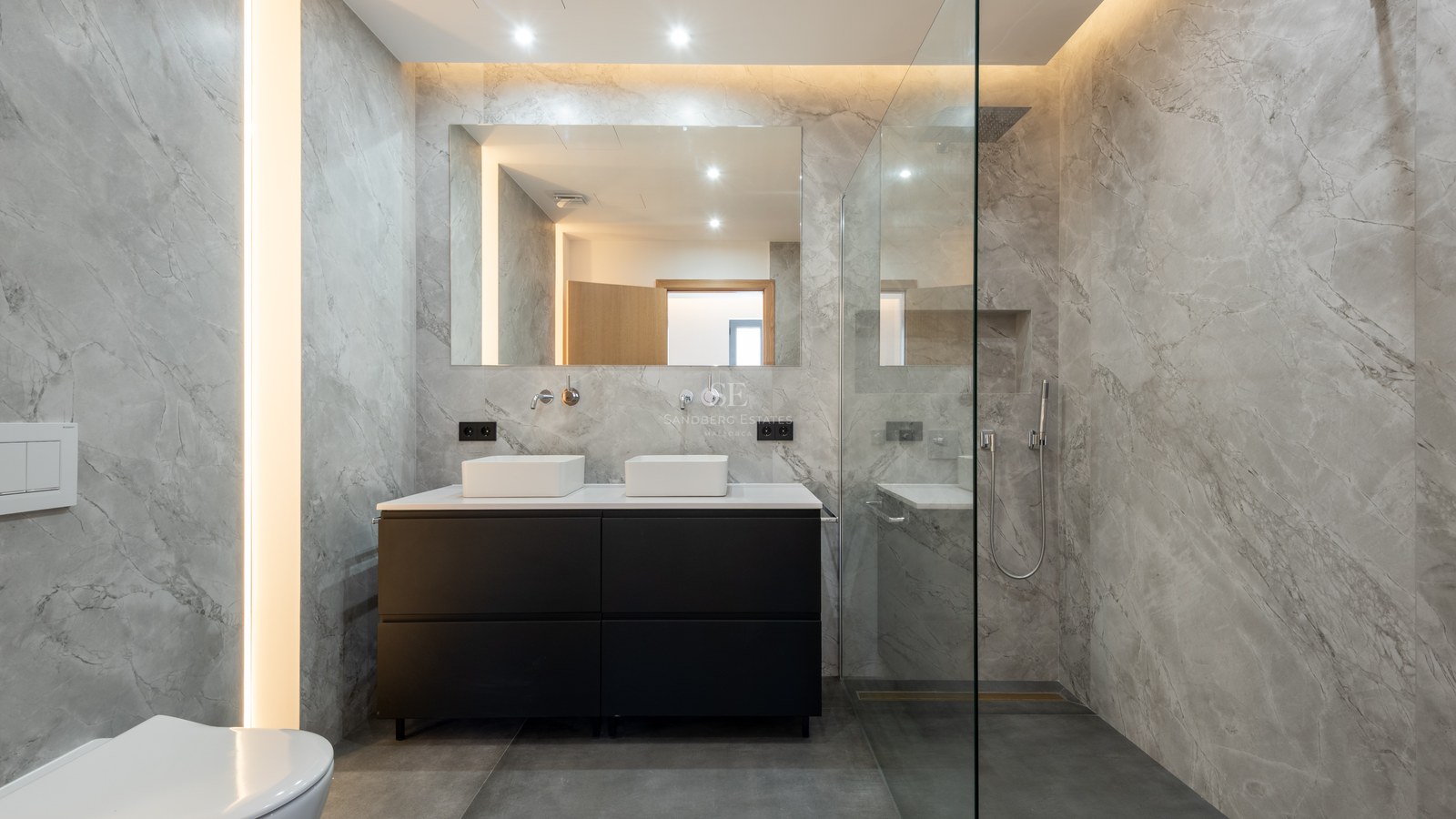Elegant bathroom with gray marble walls, black double vanity, and glass walk-in shower.