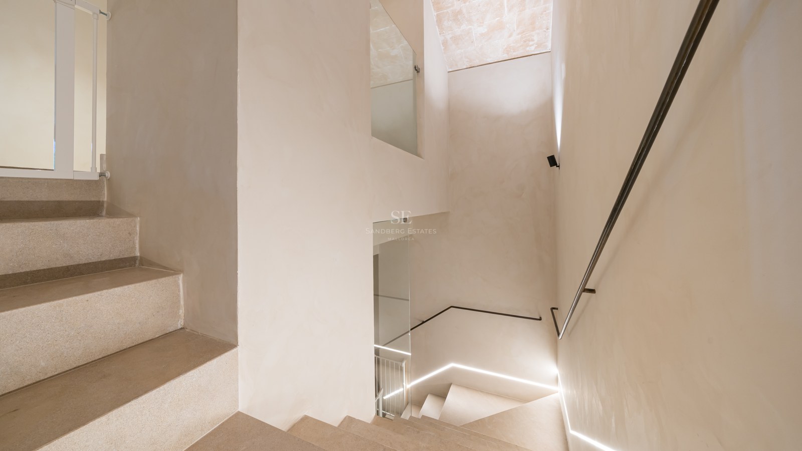 Minimalist design stone staircase with a slim metal handrail and integrated LED floor lighting.