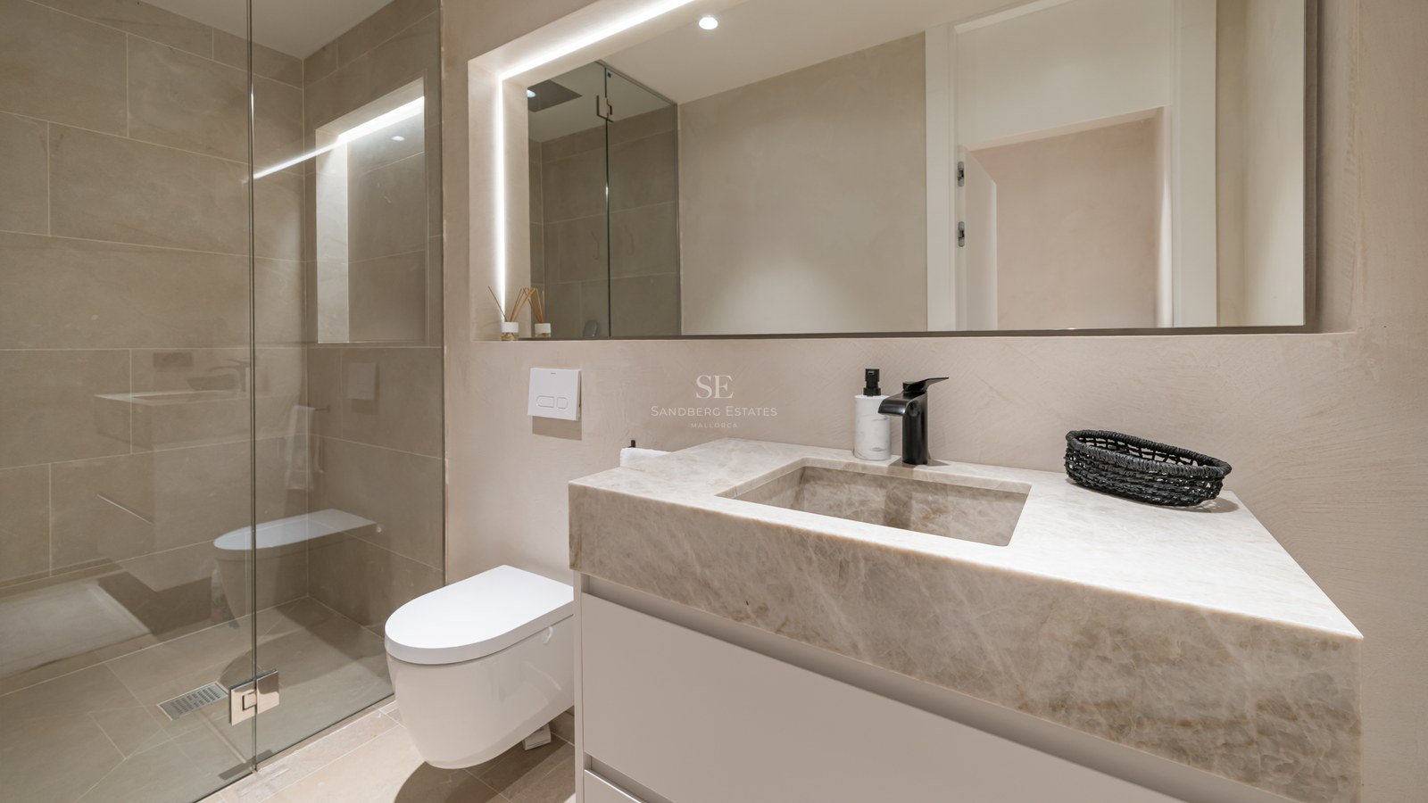 Modern bathroom featuring a stone vanity with integrated sink, black faucet, backlit mirror, and glass walk-in shower.