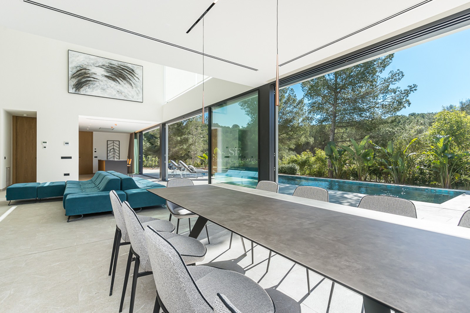 Utomhusvy av modern villa med infinitypool, solstolar, gräsmatta och panoramautsikt. Minimalistisk arkitektur med stora fönsterpartier.