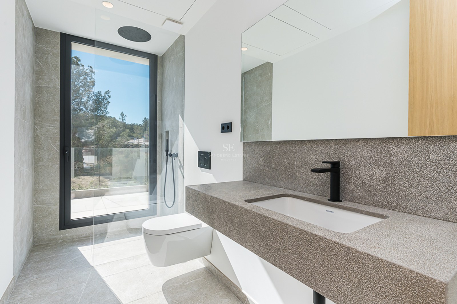 Utsikt över en lyxig villa med pool, omgiven av grönska. Modern arkitektur med stora fönsterpartier och högkvalitativa ytbehandlingar.