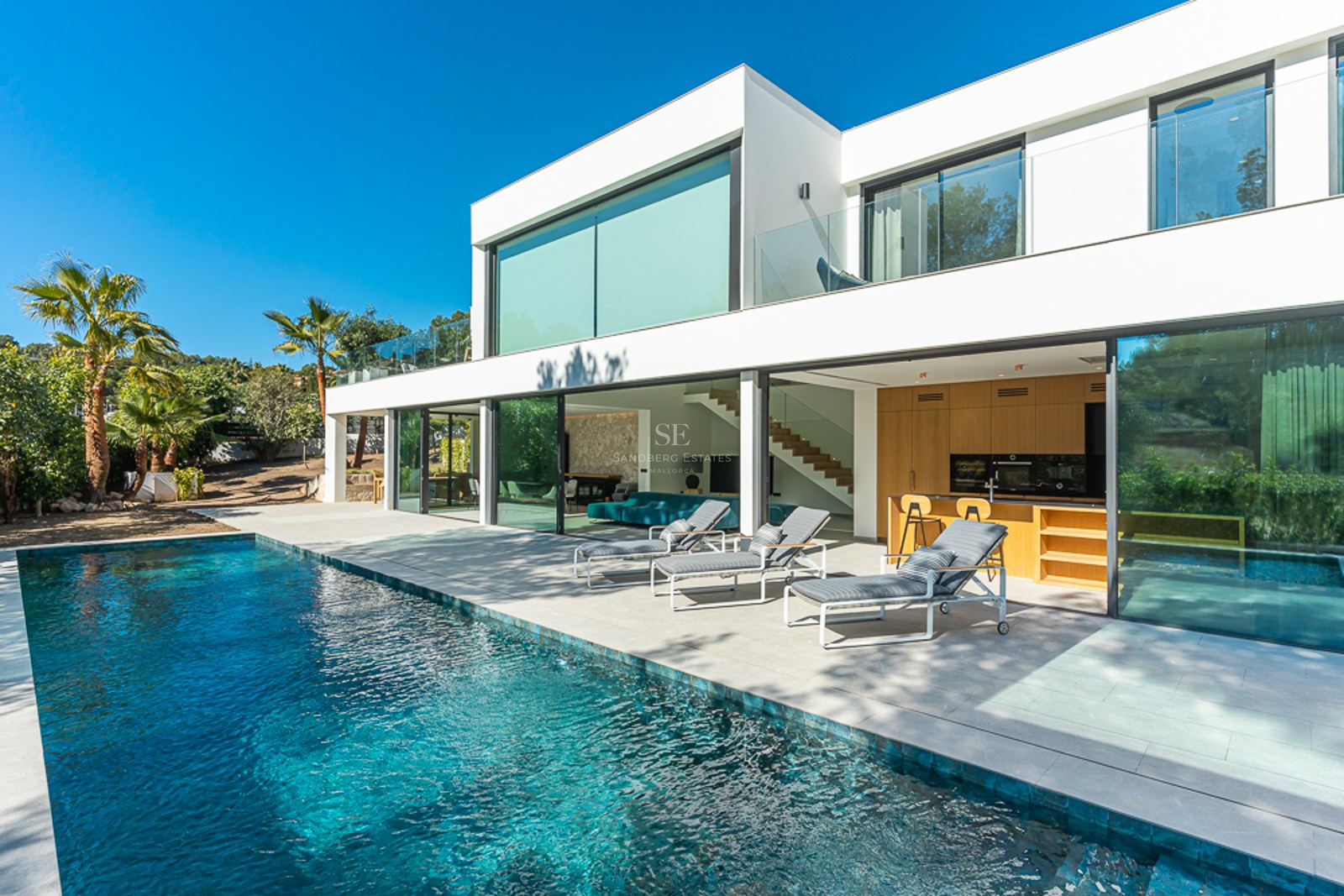 Exteriör av modern villa med pool, gräsmatta och stora fönsterpartier. Minimalistisk design med rena linjer och rikligt med naturligt ljus.
