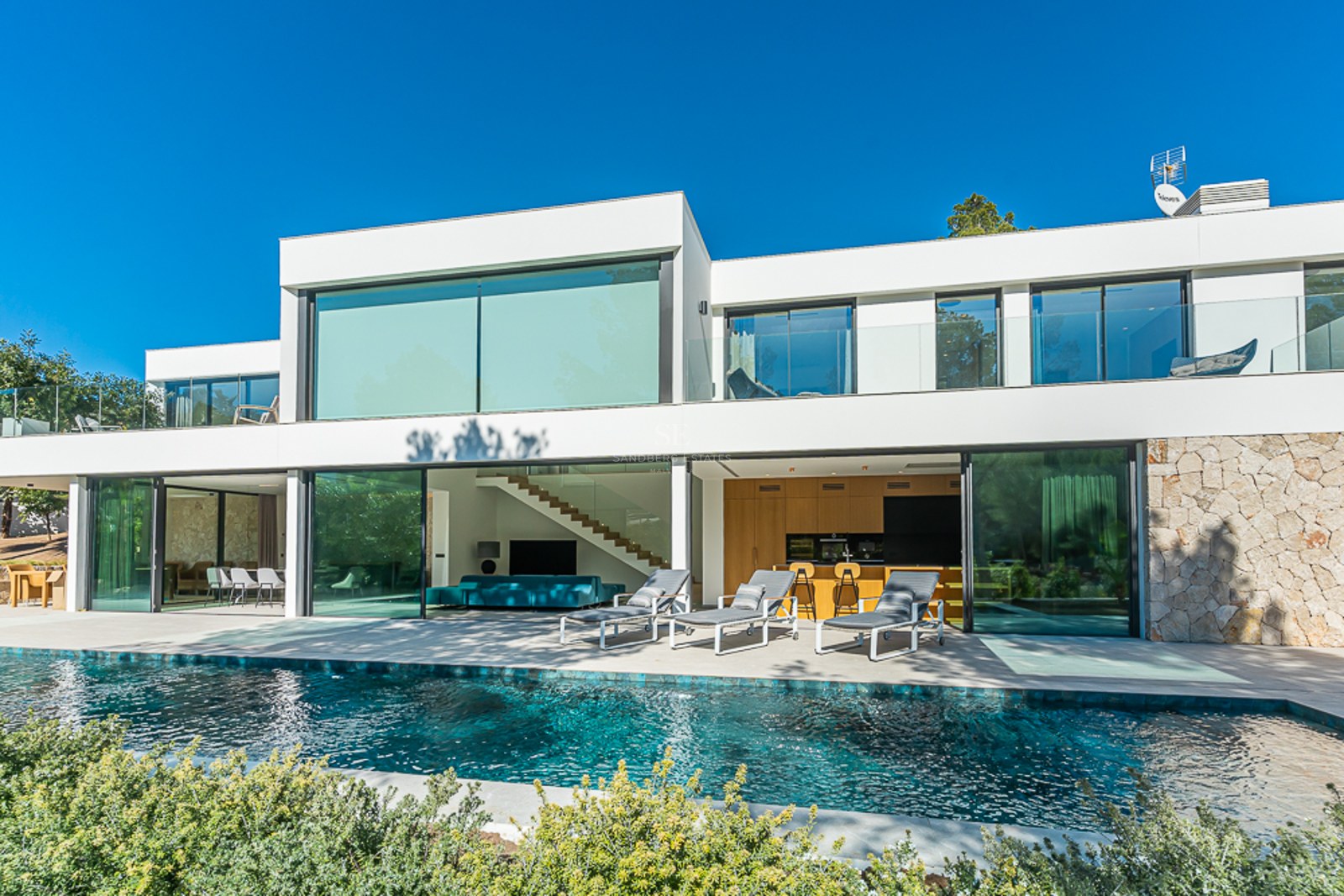 Exteriör vy av ett modernt hus med pool, lummig trädgård och stora fönster. Elegant design och högkvalitativa ytskikt.