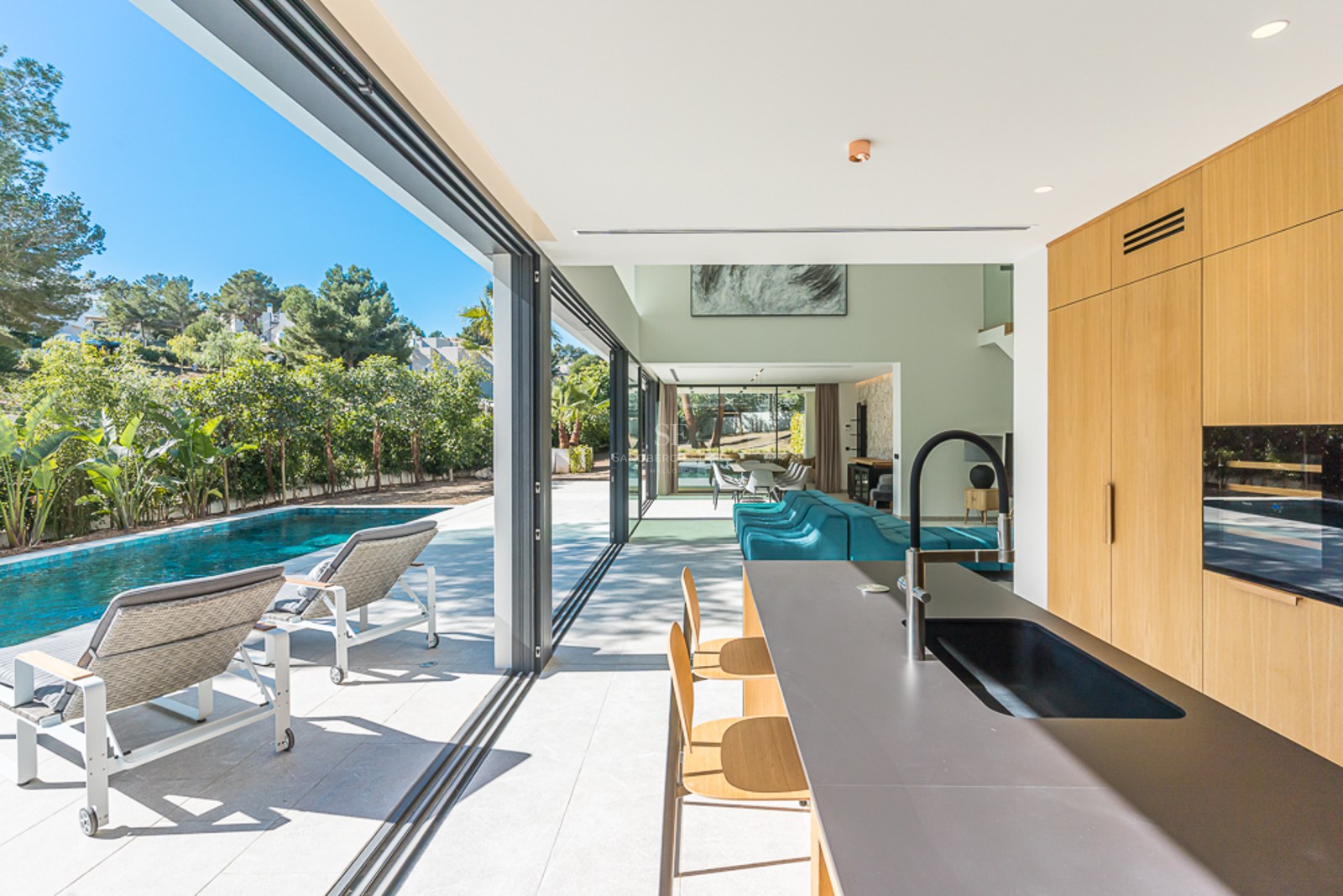 Vy av modern villa med infinitypool, solstolar och anlagd trädgård. Minimalistisk design med stora fönster och rikligt med naturligt ljus.