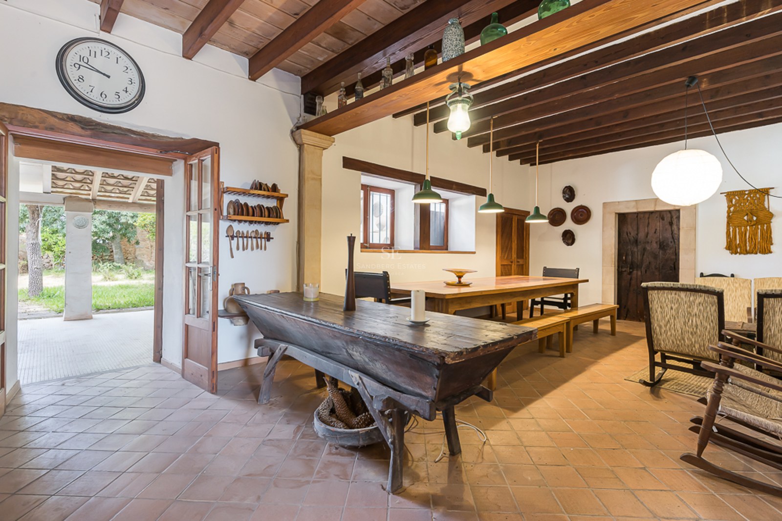 Rustic dining room with terracotta floors, exposed wooden beams, a long table, and antique furniture.