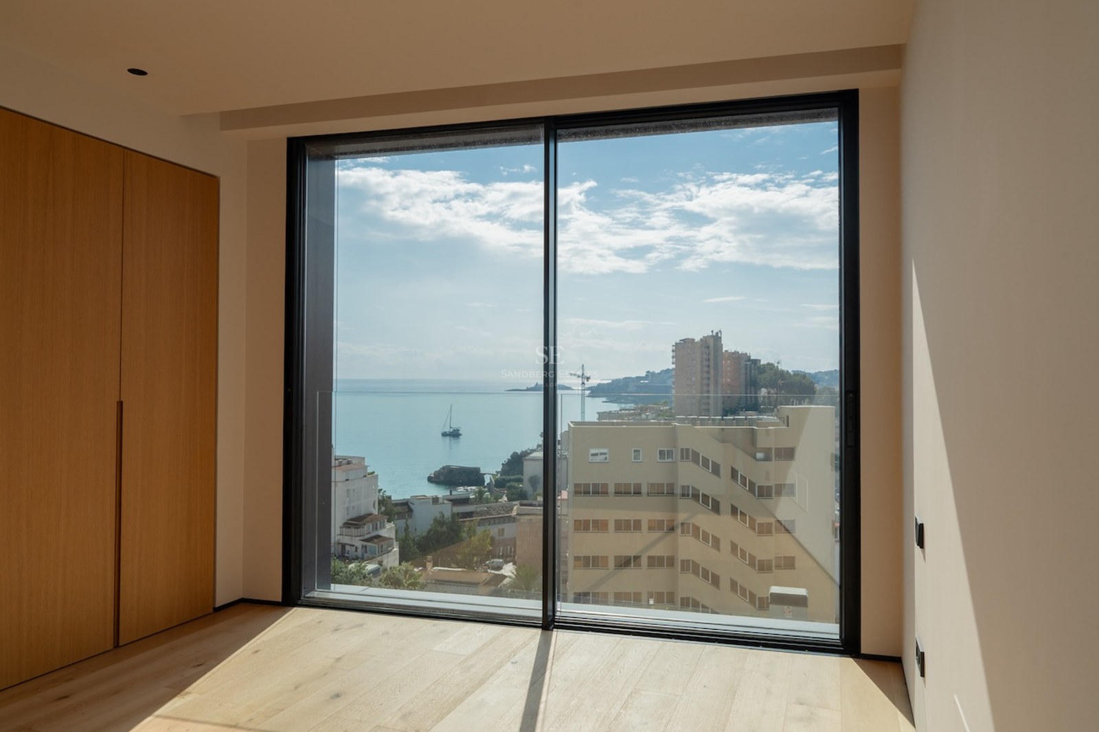 Minimalistisches Schlafzimmer mit Eichenparkett und bodentiefe Fenster mit Blick auf das Mittelmeer.