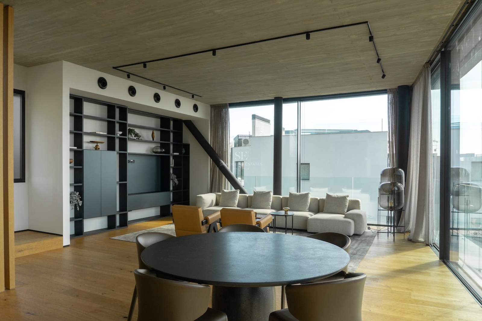 Zeitgenössisches Wohnzimmer mit bodentiefen Fenstern, Eichenparkett und Sichtbetondecke in einer Luxusimmobilie.