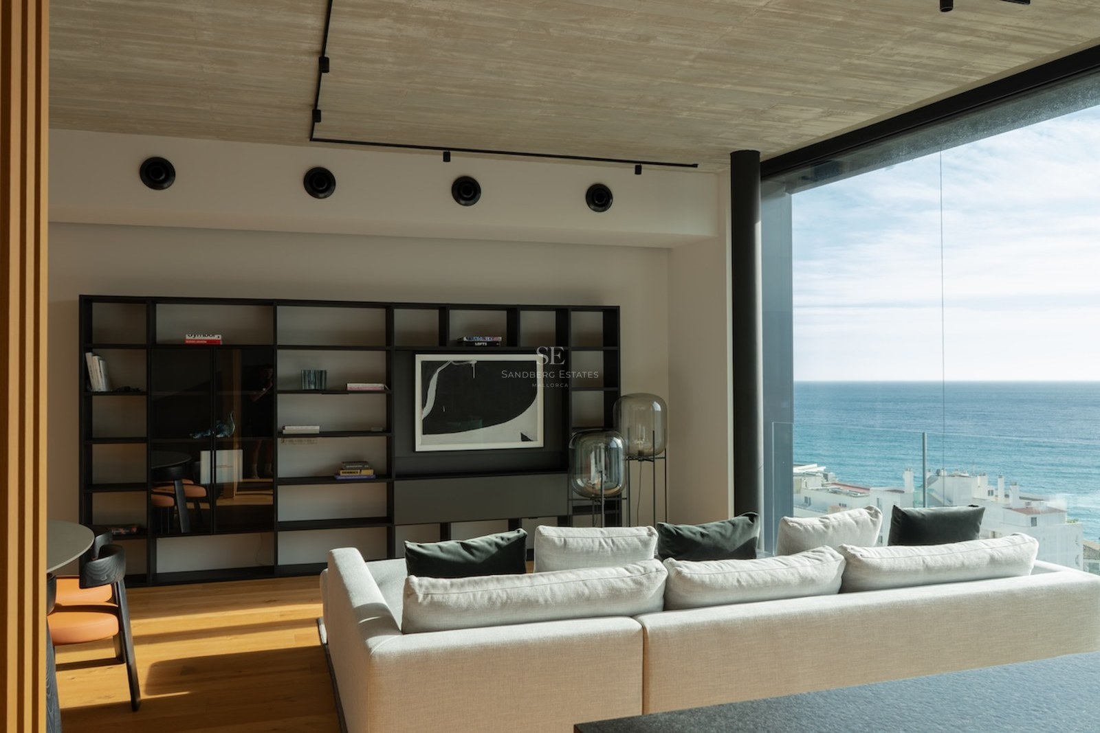 Contemporary living room featuring floor-to-ceiling windows with Mediterranean sea views, white sofa, and wooden floors.