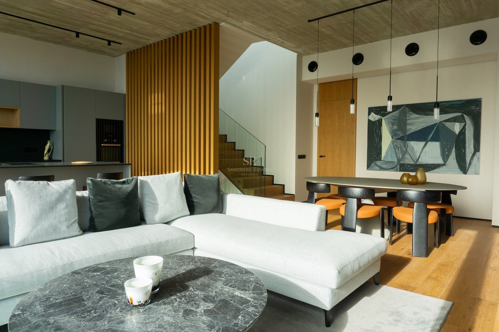 Modernes Wohnzimmer mit grauem Sofa, Marmortisch, Eichenparkett und Essbereich unter Sichtbetondecke.