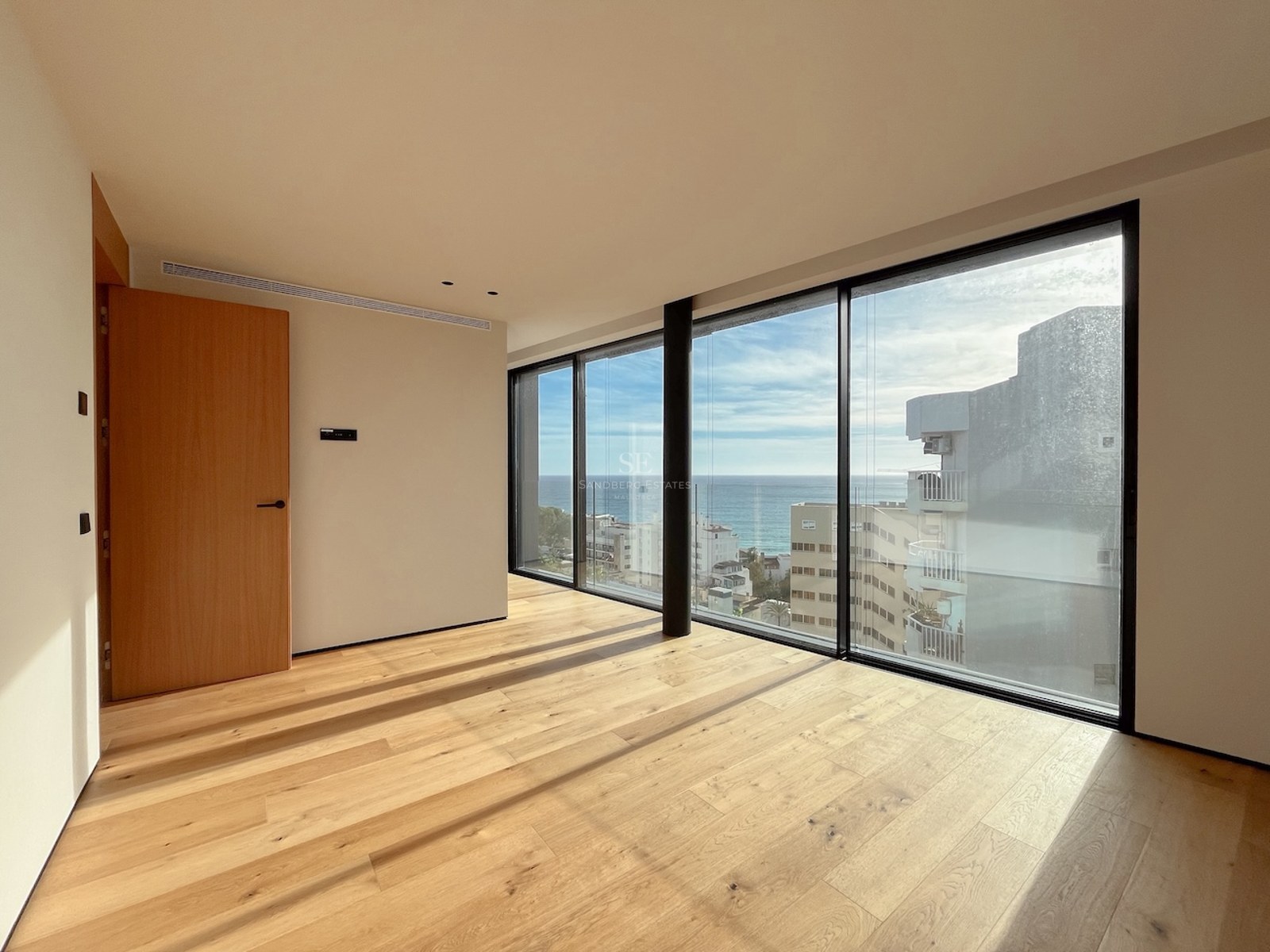 Leeres modernes Schlafzimmer mit Eichenboden und großen Fensterfronten mit Blick auf das Mittelmeer.
