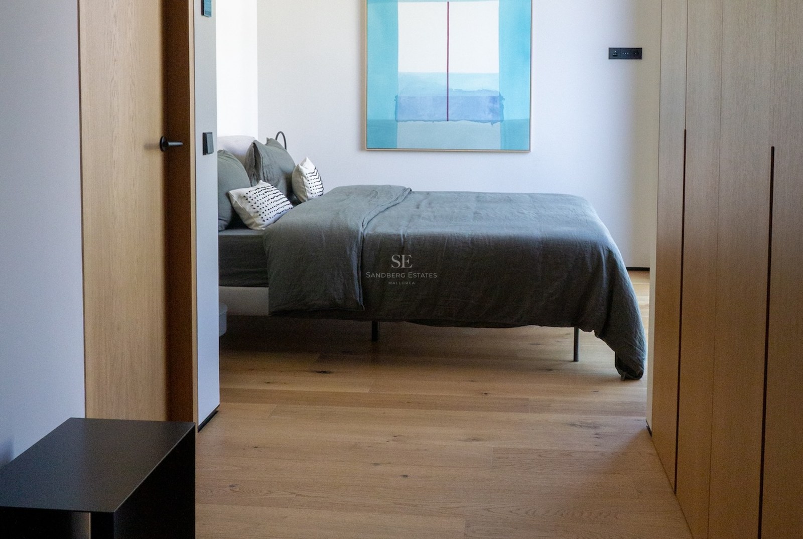 Zeitgenössisches Schlafzimmer mit salbeigrüner Leinenbettwäsche, Eichenholzböden und Einbauschränken.