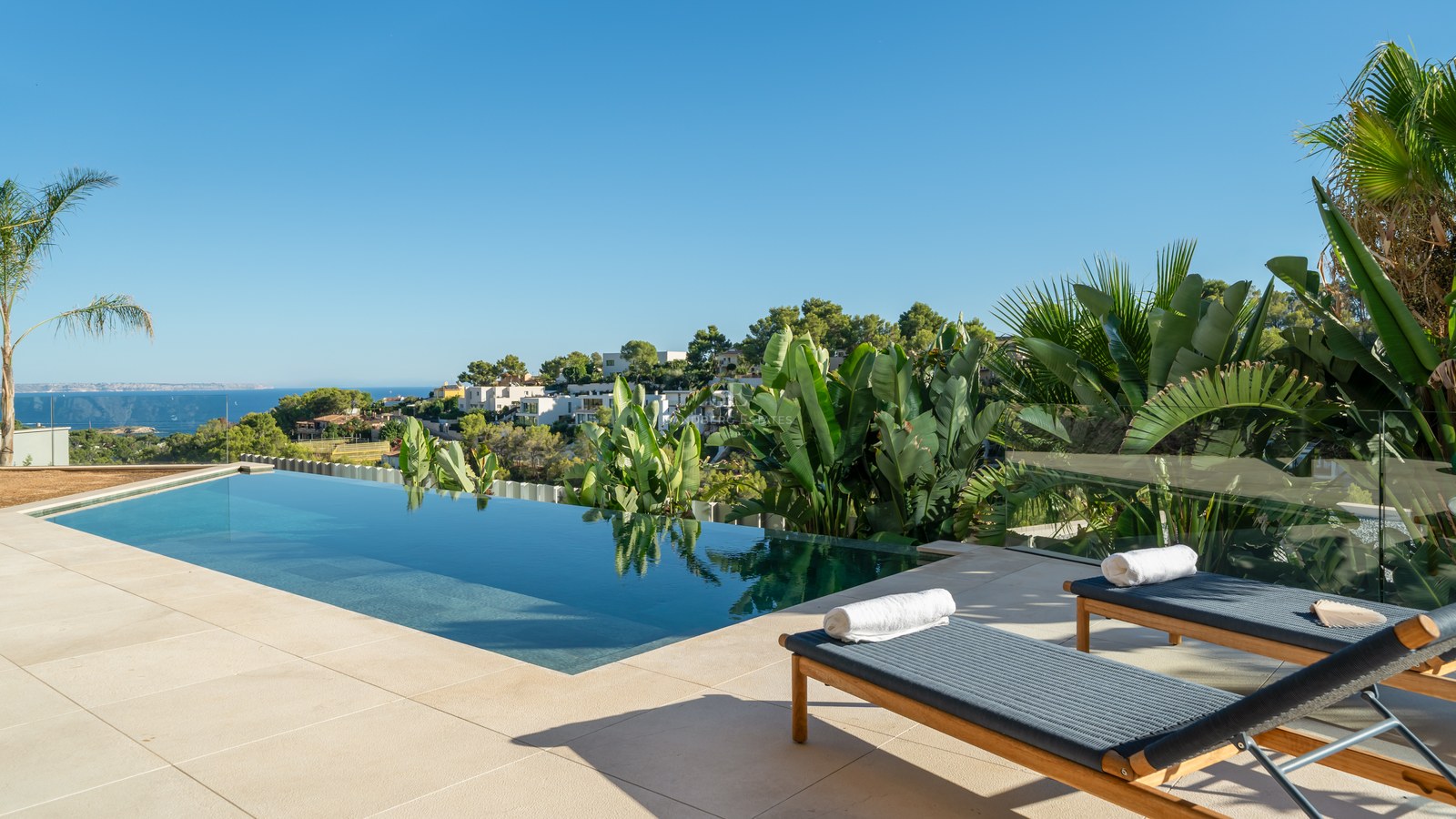 Spacious outdoor area with pool, manicured lawn, sun loungers, and lush vegetation. Ideal for relaxation and entertainment.