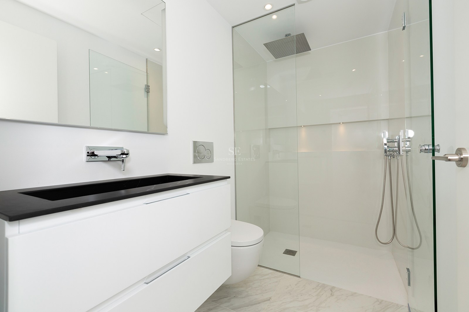 Clean white bathroom featuring a walk-in glass shower, black stone vanity, and marble-effect floor tiles.