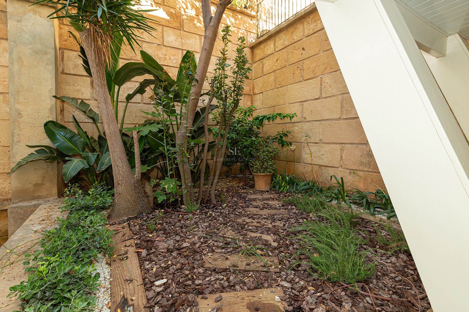 Natural stone wall with tropical plants and wood mulch in a private courtyard.