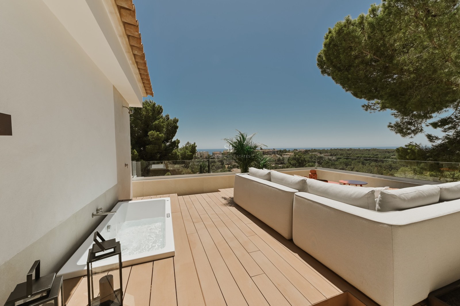 Terraza contemporánea con tarima de madera, piscina de inmersión, sofás de diseño y vistas panorámicas al mar.