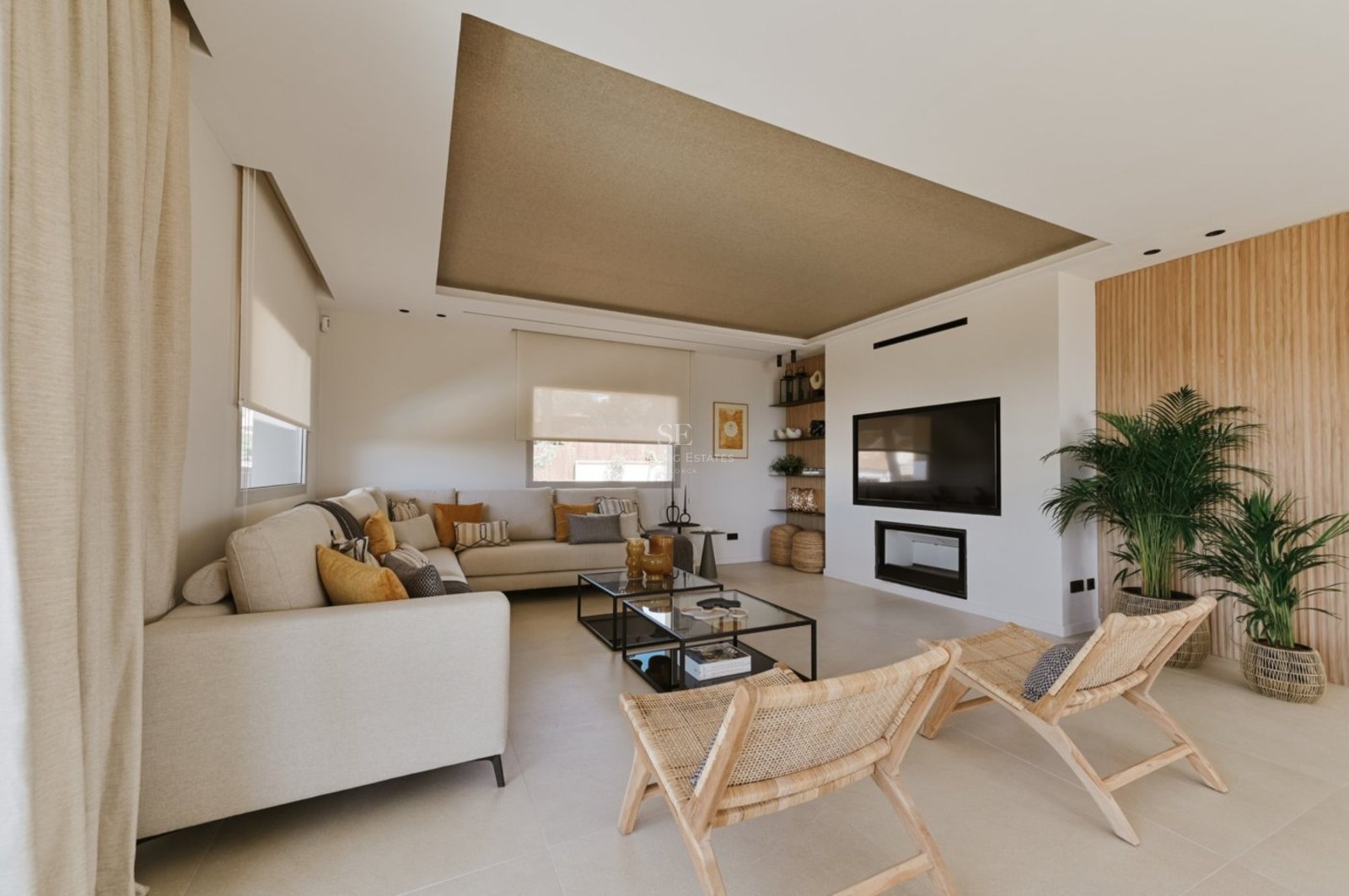 Salón contemporáneo con sofá en L color crema, sillas de madera, mesas de cristal y chimenea empotrada.