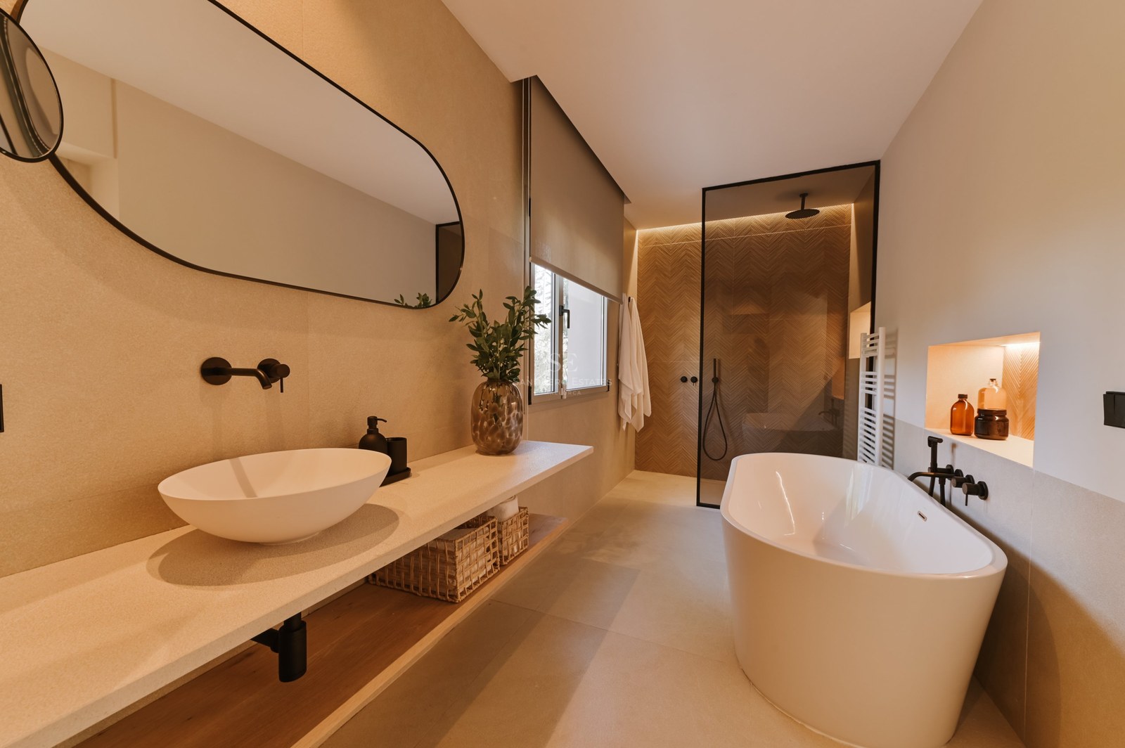Baño moderno con bañera blanca exenta, encimera flotante de piedra y ducha de obra con mampara de cristal.
