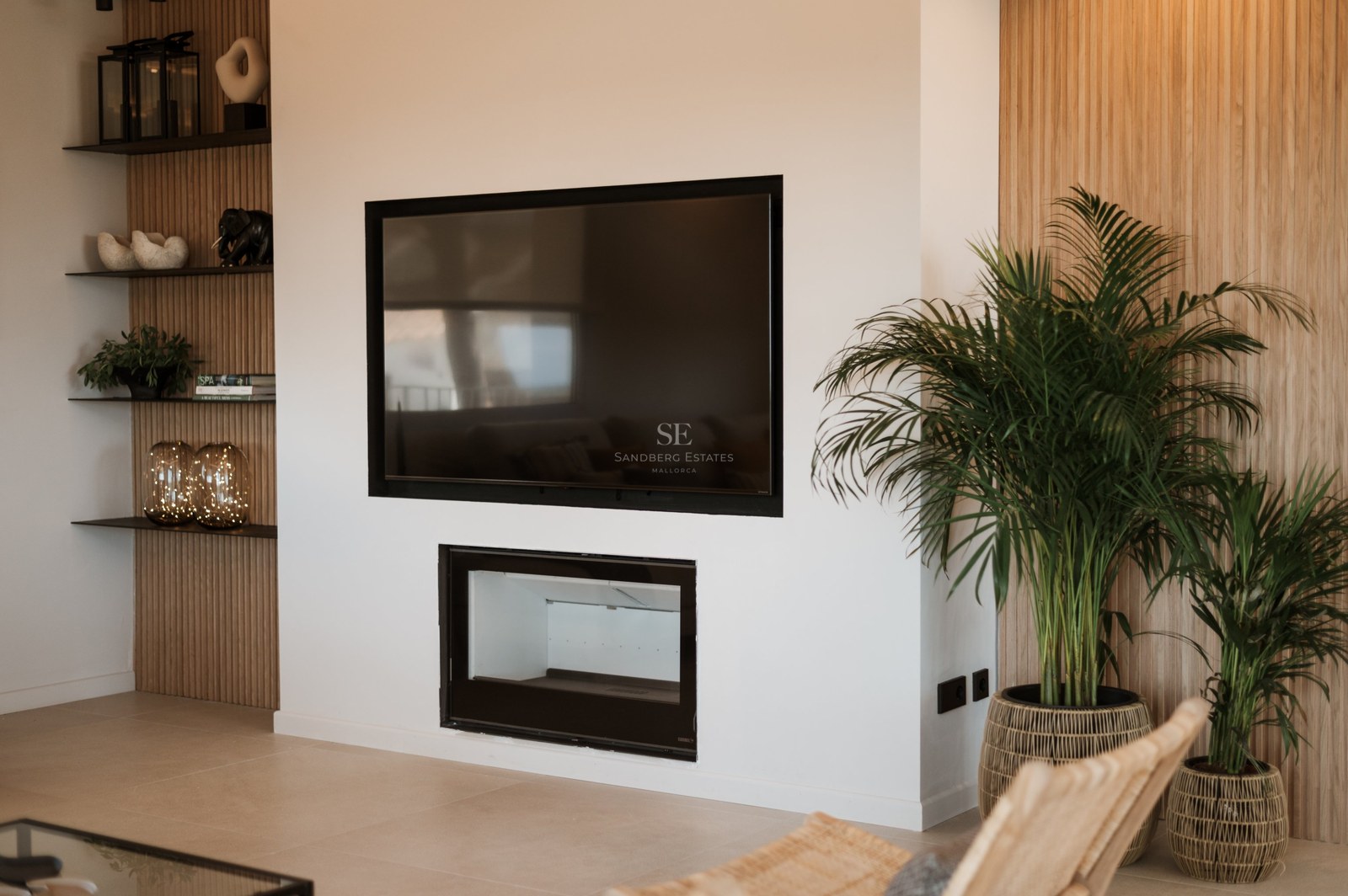 Pared blanca con televisión de pantalla plana sobre una chimenea minimalista integrada y paneles de madera de roble.