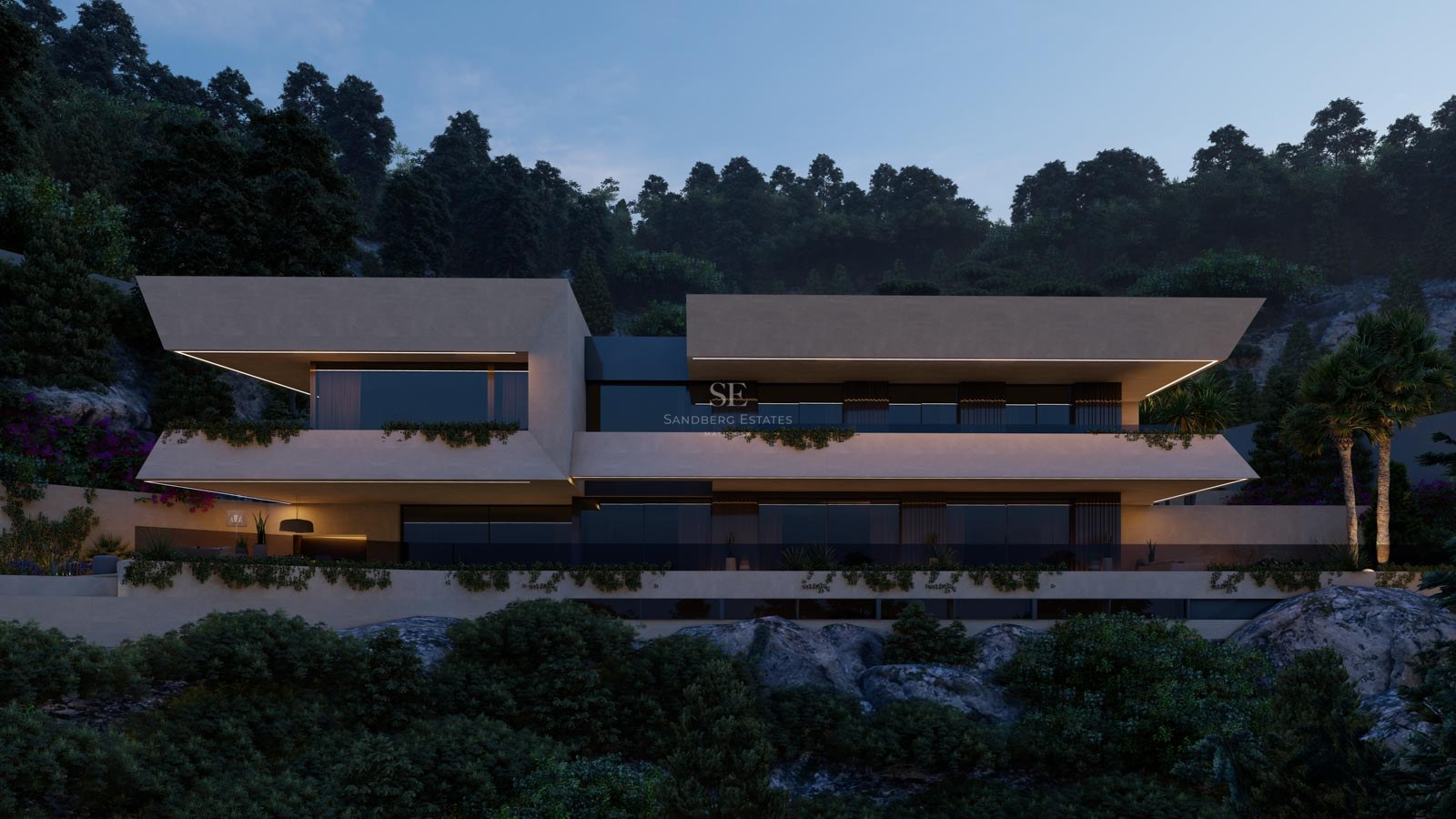 Vista nocturna de una villa moderna de varios niveles con voladizos, iluminación LED y vegetación en una ladera rocosa.