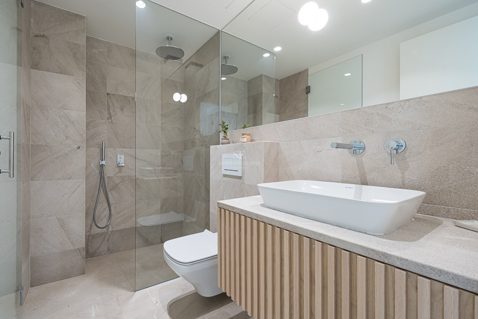 Baño contemporáneo con azulejos de piedra beige, ducha de cristal y mueble de lavabo con listones de madera.