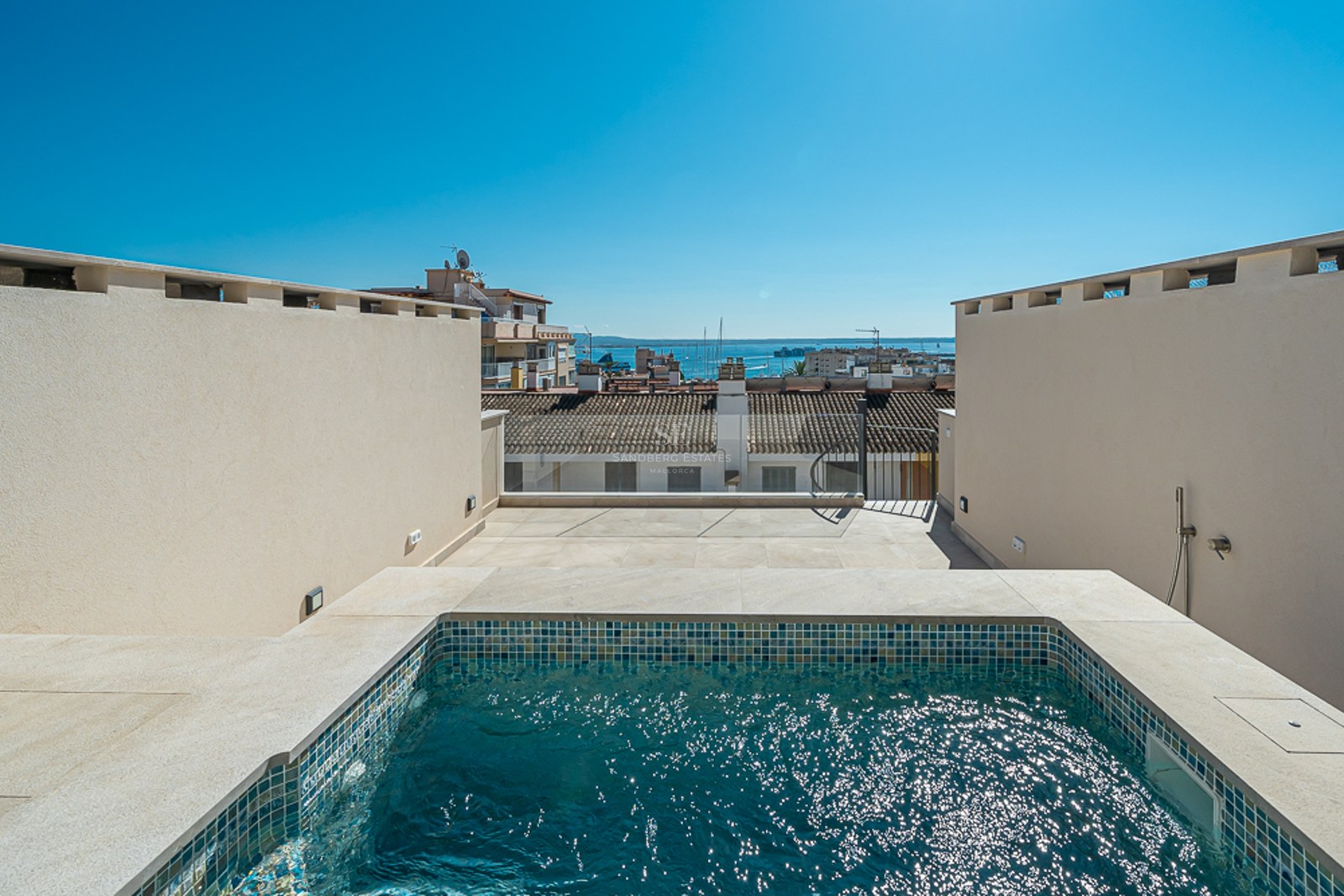 Piscina privada tipo plunge en una azotea con azulejos de mosaico azul y vistas panorámicas al puerto y la ciudad.