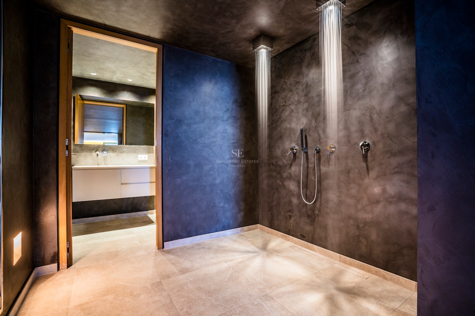Modern walk-in shower with dual ceiling-mounted rainfall heads and charcoal micro-cement walls.