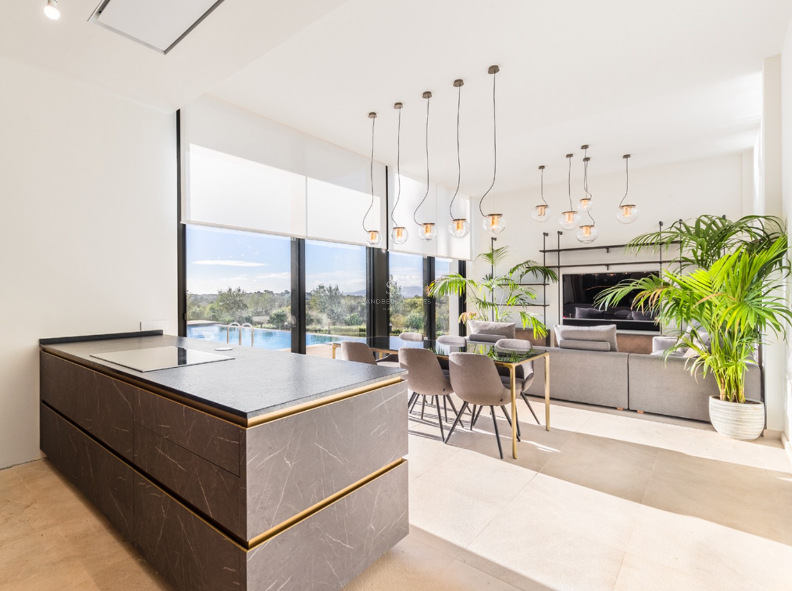 Salon moderne à aire ouverte avec îlot de cuisine en marbre gris, salle à manger et baies vitrées donnant sur la piscine.