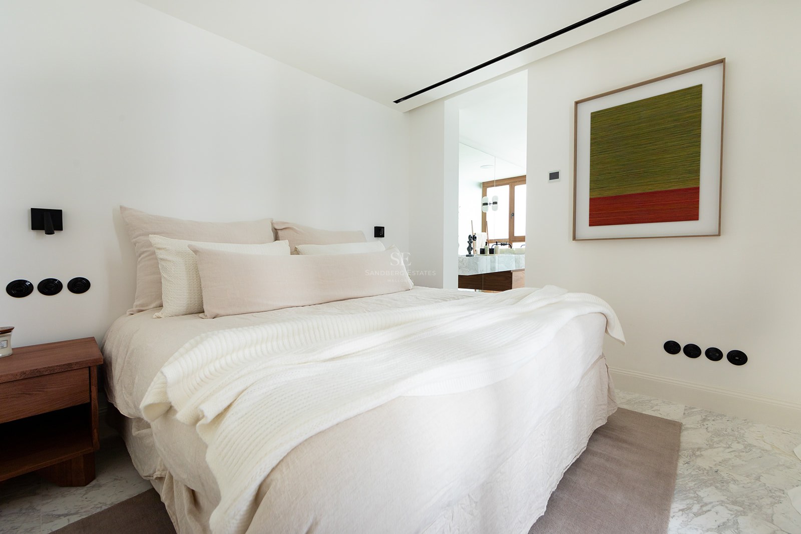 Dormitorio principal contemporáneo con cama grande, suelos de mármol y vista al baño privado con acabados en madera.