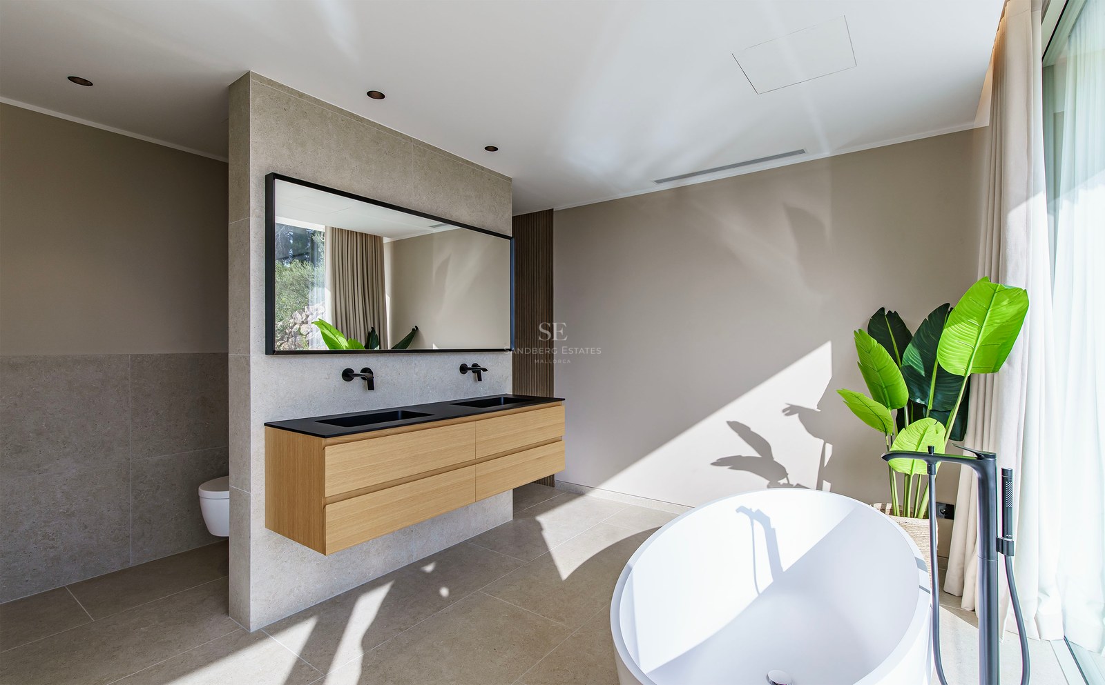 Salle de bain principale spacieuse avec baignoire blanche, double vasque suspendue en bois et robinetterie noire.