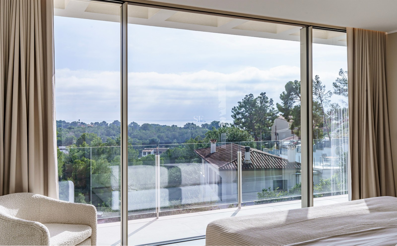 Chambre de luxe avec baies vitrées offrant une vue sur le paysage méditerranéen et la mer.
