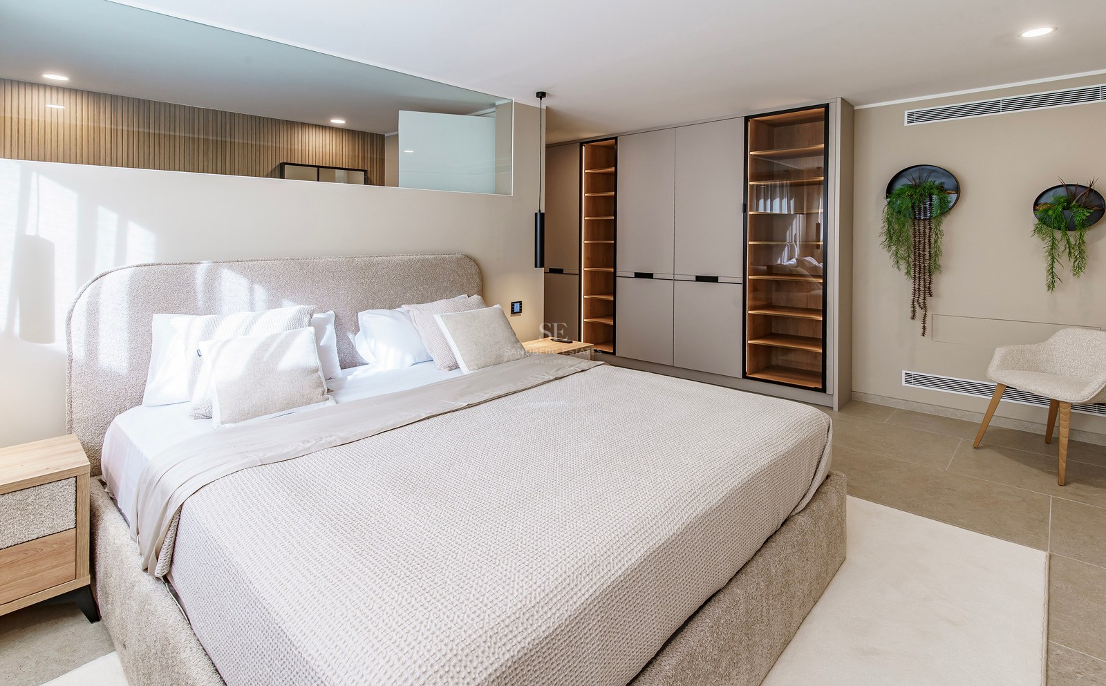 Chambre principale moderne avec grand lit rembourré, armoires encastrées avec éclairage LED et décor neutre.