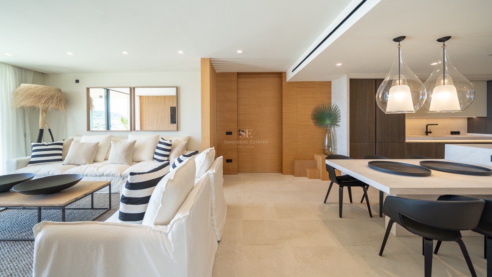 Salon élégant avec canapés en lin blanc, boiseries en chêne et coin repas avec suspensions design.