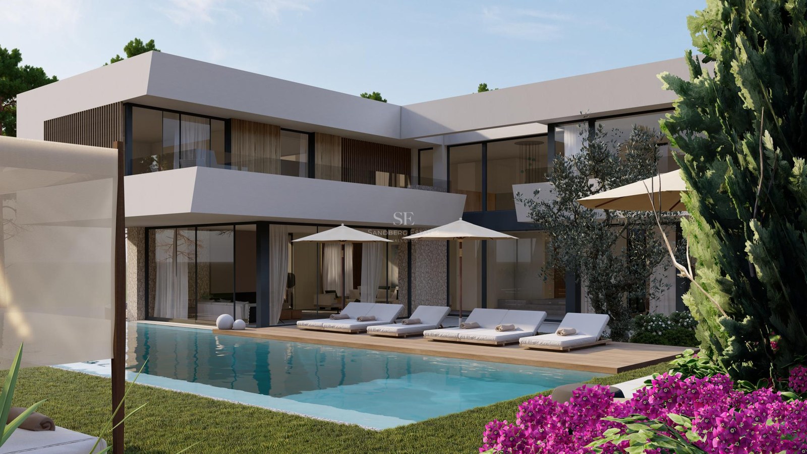 Contemporary two-story white villa with an infinity pool, wooden deck, sun loungers, and lush green landscaping.